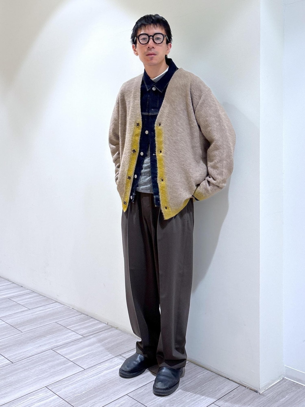 イエロー系のカーディガン/ボレロ、ブルー系のデニムジャケット、グレー系のニット/セーターを着用したメンズの秋コーディネートの1枚目の写真