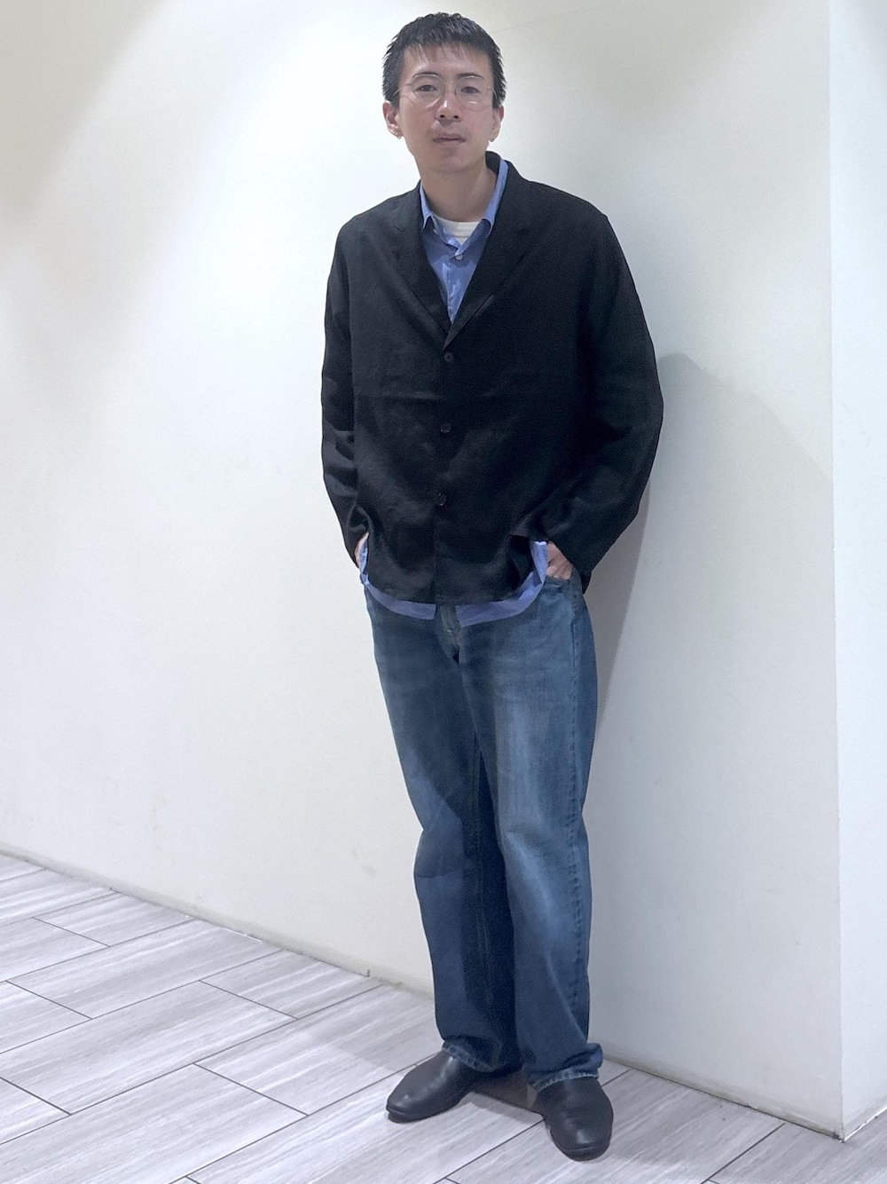 ブルー系のデニムパンツ、ブラック系のテーラードジャケットを着用したメンズの春コーディネートの1枚目の写真