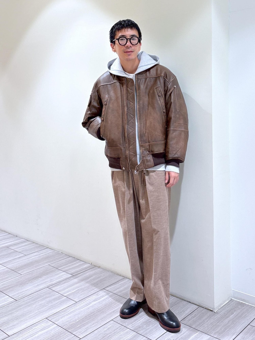 ブラック系のブーツ、グレー系のパーカー、ベージュ系のスラックスを着用したメンズの秋コーディネートの1枚目の写真