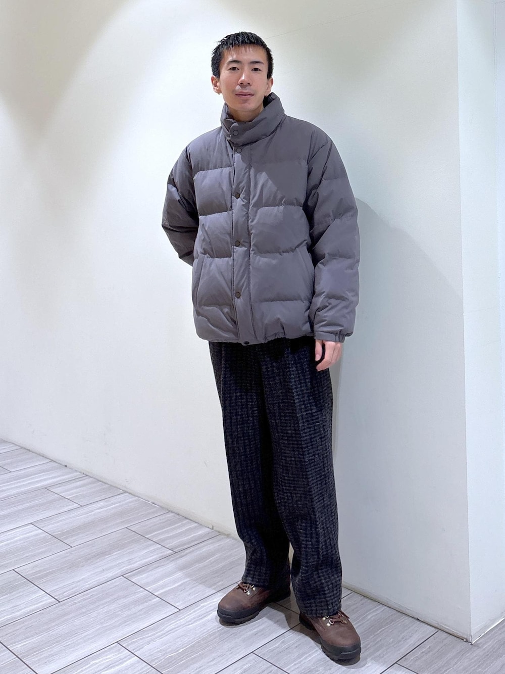 グレー系のダウンジャケット/コート、グレー系のスラックス、ブラウン系のブーツを着用したメンズの冬コーディネートの1枚目の写真
