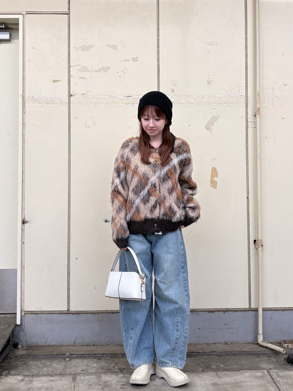 ブラウン系のカーディガン/ボレロ、ブルー系のデニムパンツ、ホワイト系のショルダーバッグを着用したレディースの冬コーディネートの1枚目の写真
