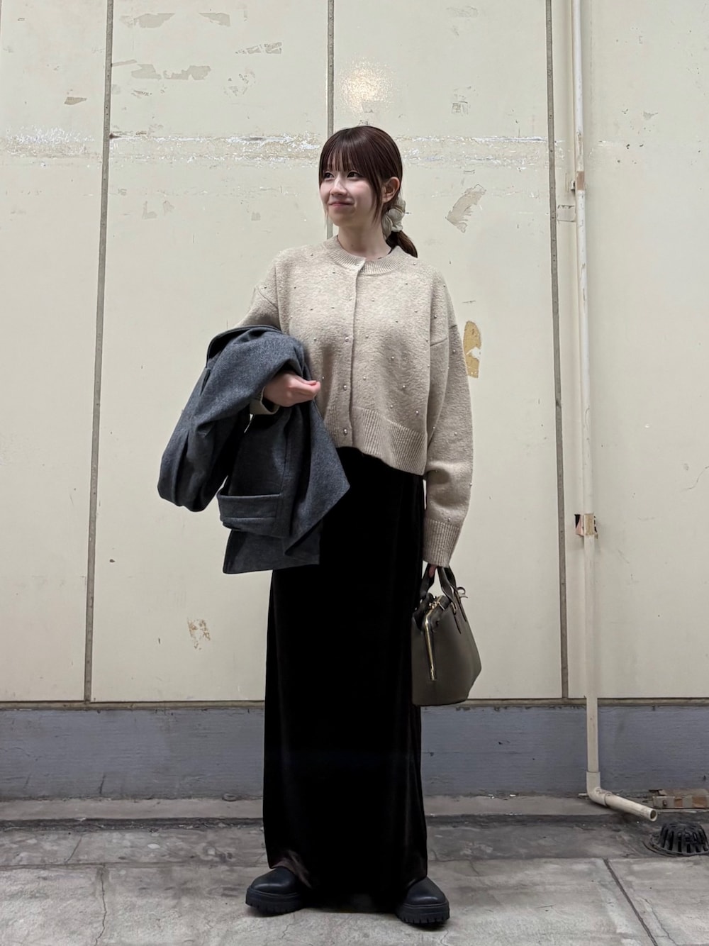 ベージュ系のカーディガン/ボレロ、ブラック系のブーツ、ブラウン系のトートバッグを着用したレディースの秋コーディネートの1枚目の写真