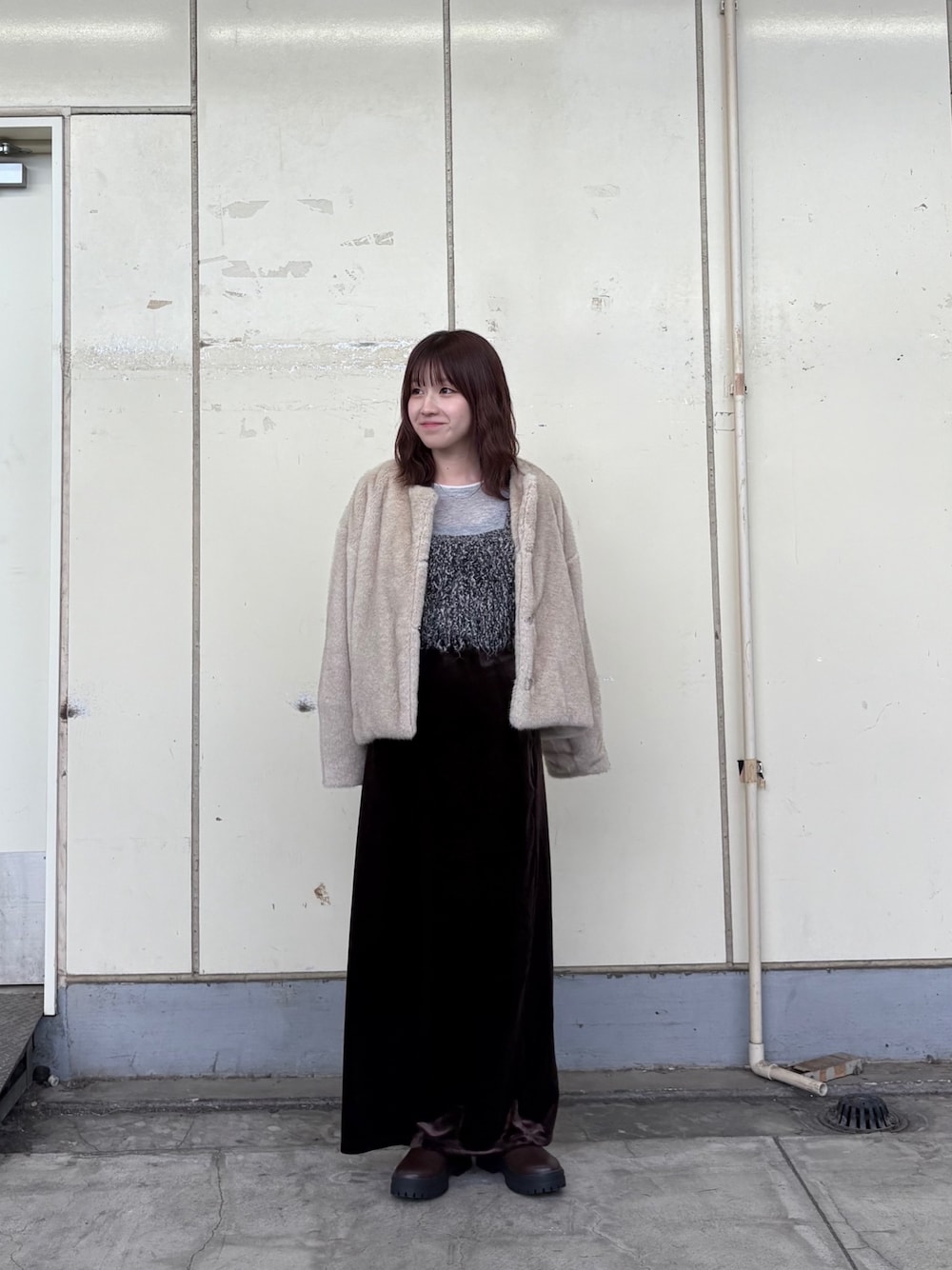ブラック系のニット/セーター、グレー系のTシャツ/カットソー、ブラウン系のスカートを着用したレディースの秋コーディネートの1枚目の写真