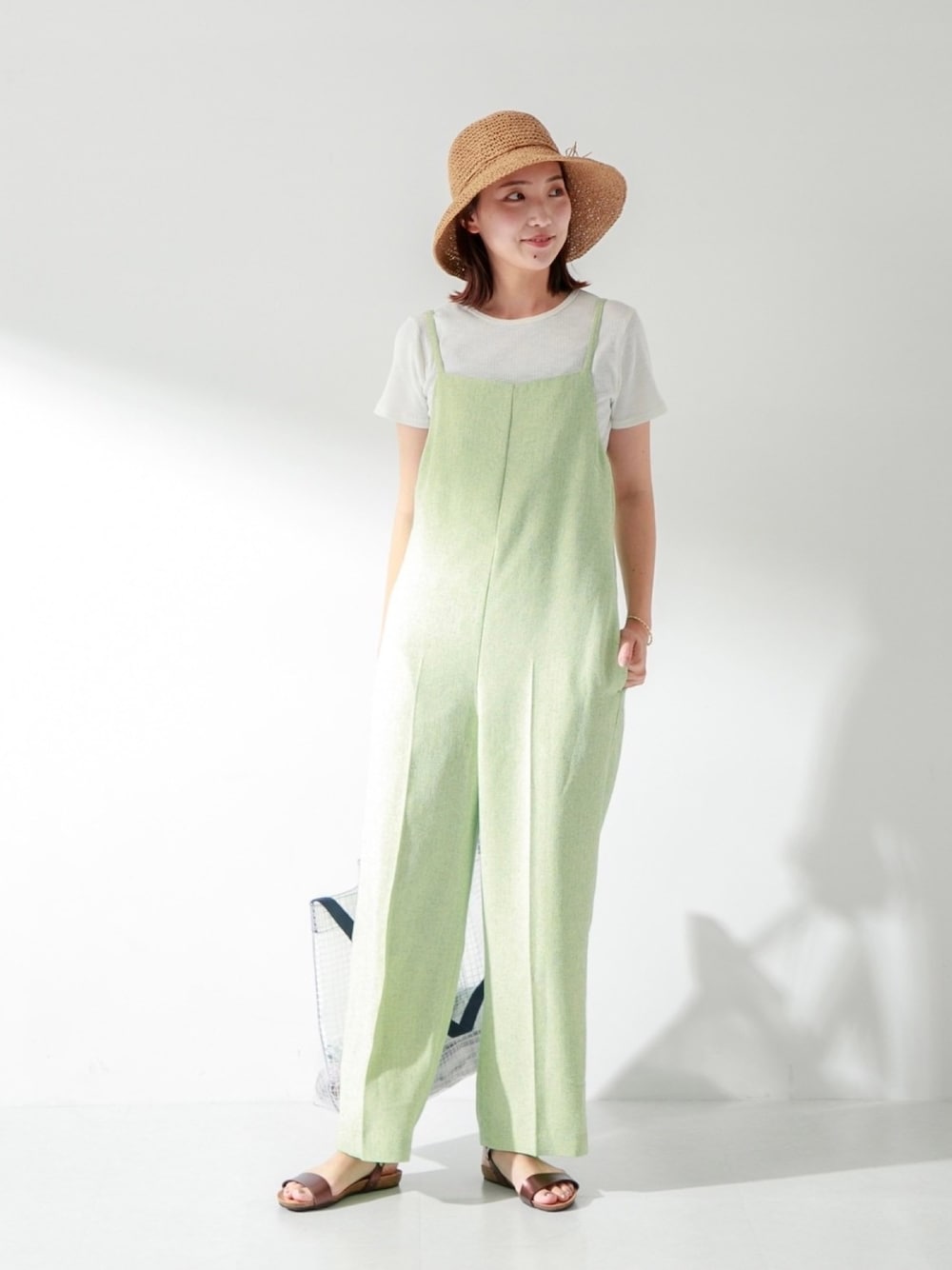 グリーン系のサロペット/オーバーオール、ホワイト系のTシャツ/カットソー、ブラウン系のサンダルを着用したレディースの夏コーディネートの1枚目の写真