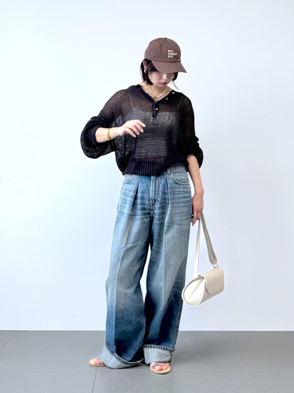 ブルー系のデニムパンツ、ホワイト系のショルダーバッグ、ホワイト系のキャミソールを着用したレディースの春コーディネートの1枚目の写真