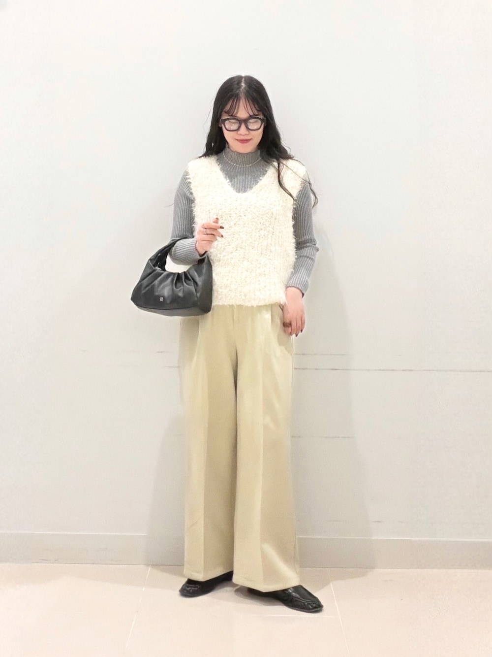 グレー系のニット/セーター、ベージュ系のその他パンツ、ホワイト系のベストを着用したレディースの秋コーディネートの1枚目の写真