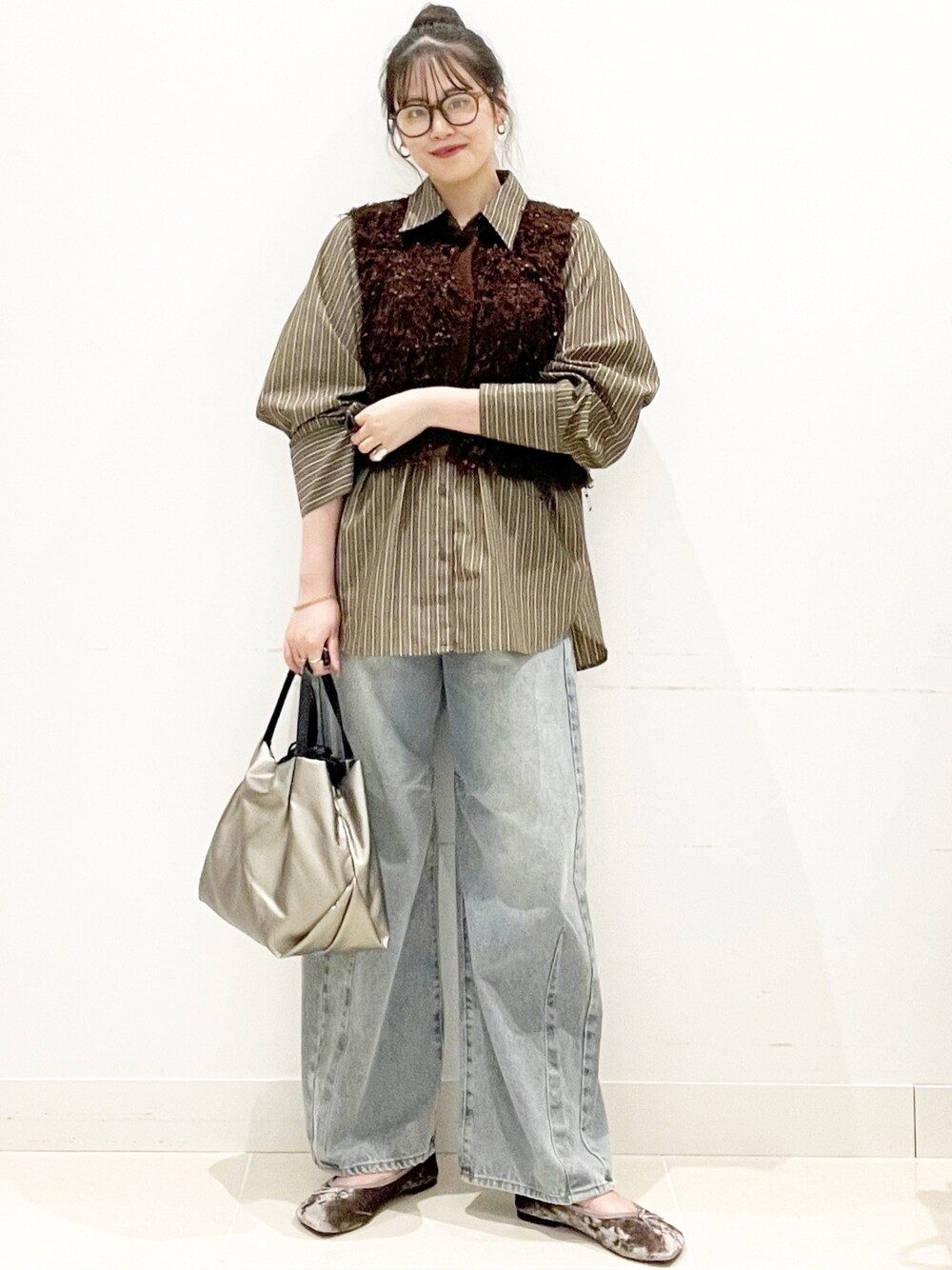 グレー系のバレエシューズ、ブルー系のデニムパンツ、シルバー系のショルダーバッグを着用したレディースの秋コーディネートの1枚目の写真
