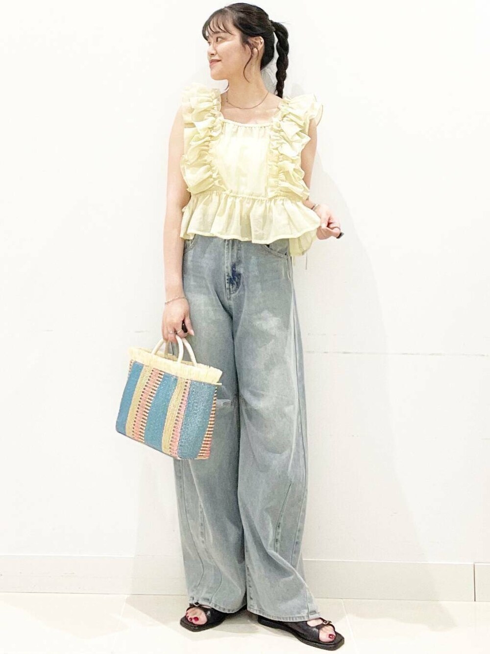 ホワイト系のキャミソール、ブルー系のデニムパンツ、ベージュ系のショルダーバッグを着用したレディースの夏コーディネートの1枚目の写真