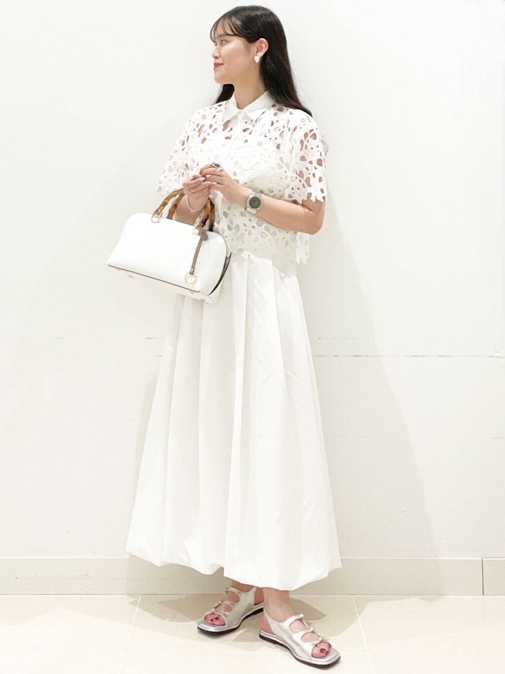ホワイト系のスカート、ホワイト系のキャミソール、ホワイト系のハンドバッグを着用したレディースの夏コーディネートの1枚目の写真