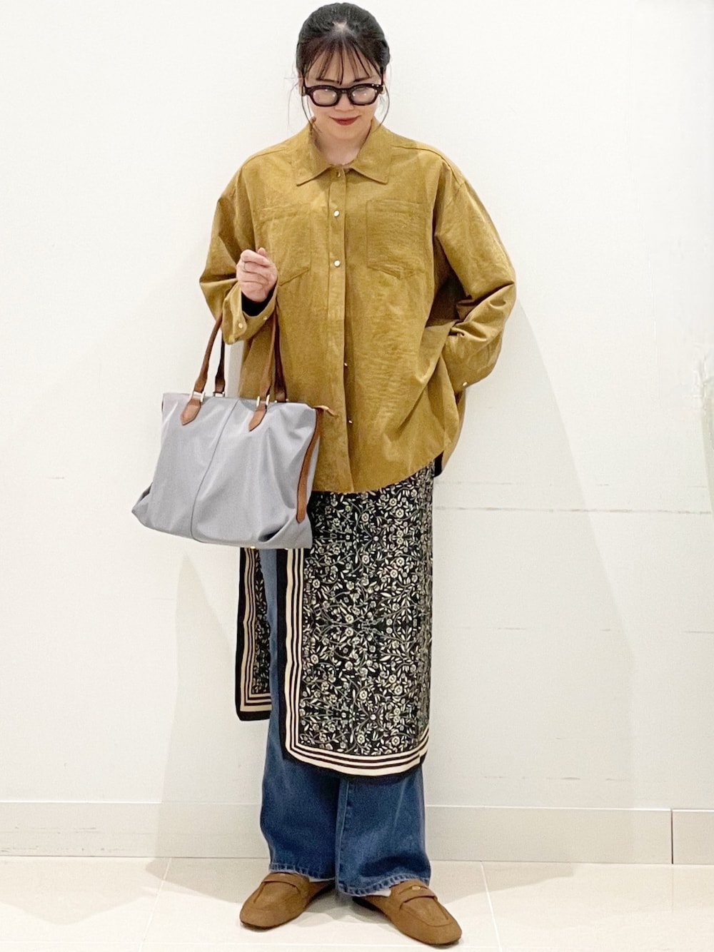 ブルー系のデニムパンツ、グレー系のトートバッグ、イエロー系のシャツ/ブラウスを着用したレディースの冬コーディネートの1枚目の写真