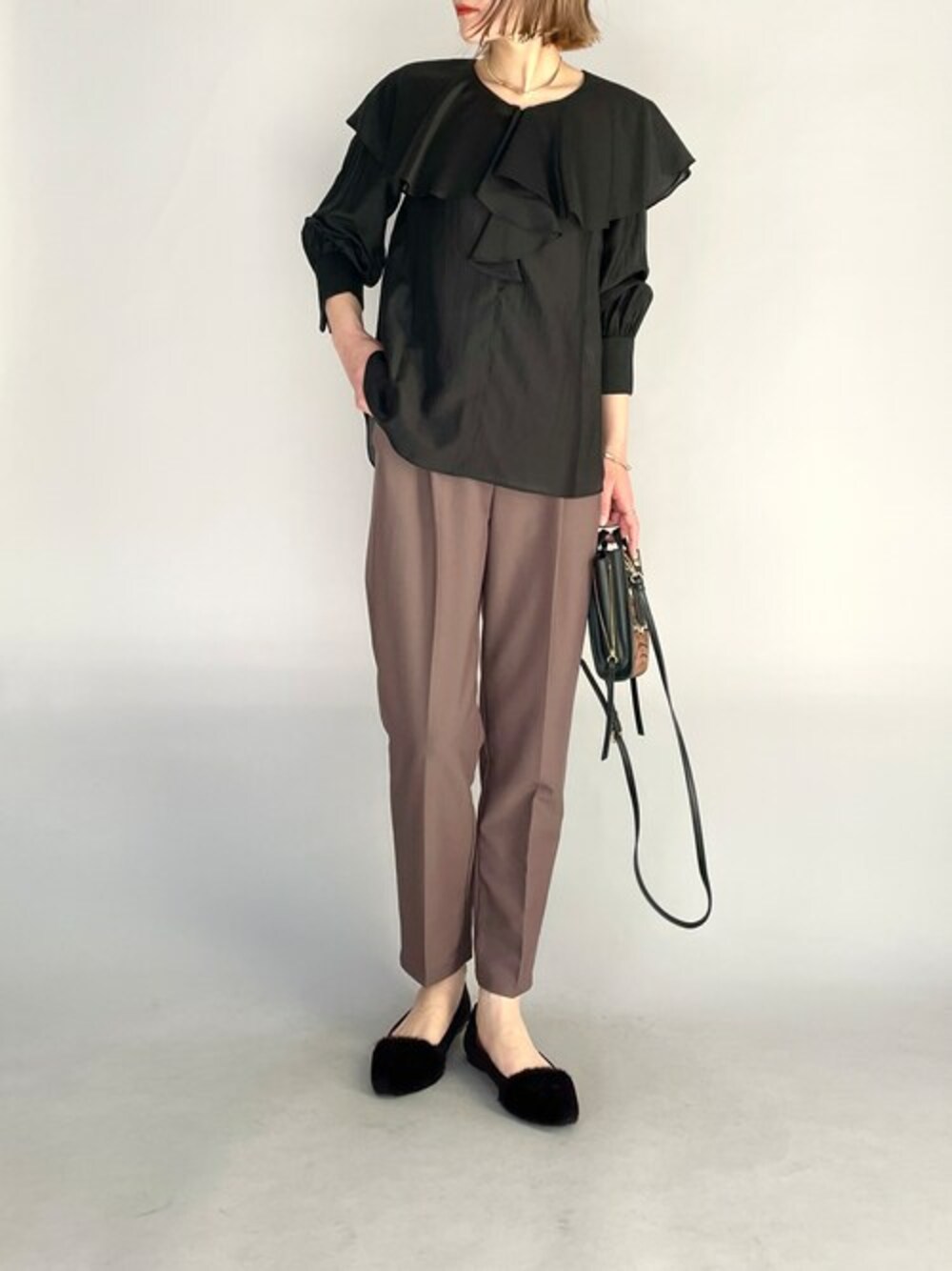 ブラック系のシャツ/ブラウス、ブラウン系のスラックスを着用したレディースの冬コーディネートの1枚目の写真