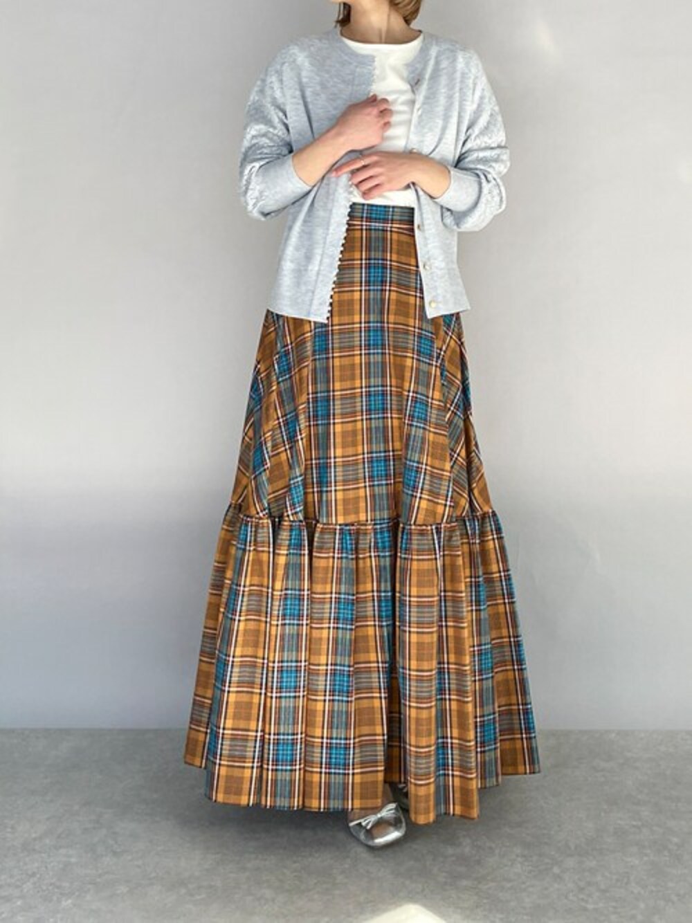 グレー系のカーディガン/ボレロ、オレンジ系のスカートを着用したレディースの春コーディネートの1枚目の写真