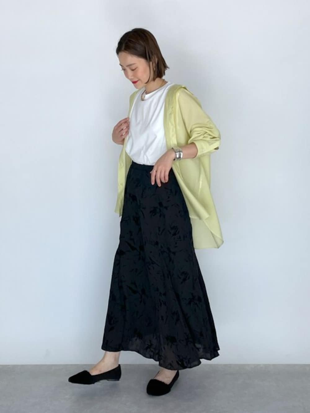 イエロー系のシャツ/ブラウス、ホワイト系のTシャツ/カットソー、ブラック系のスカートを着用したレディースの夏コーディネートの1枚目の写真
