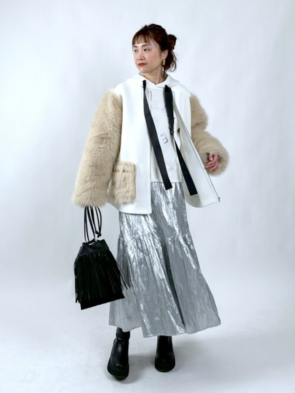 ホワイト系のノーカラーコート、ホワイト系のパーカー、シルバー系のスカートを着用したレディースの冬コーディネートの1枚目の写真