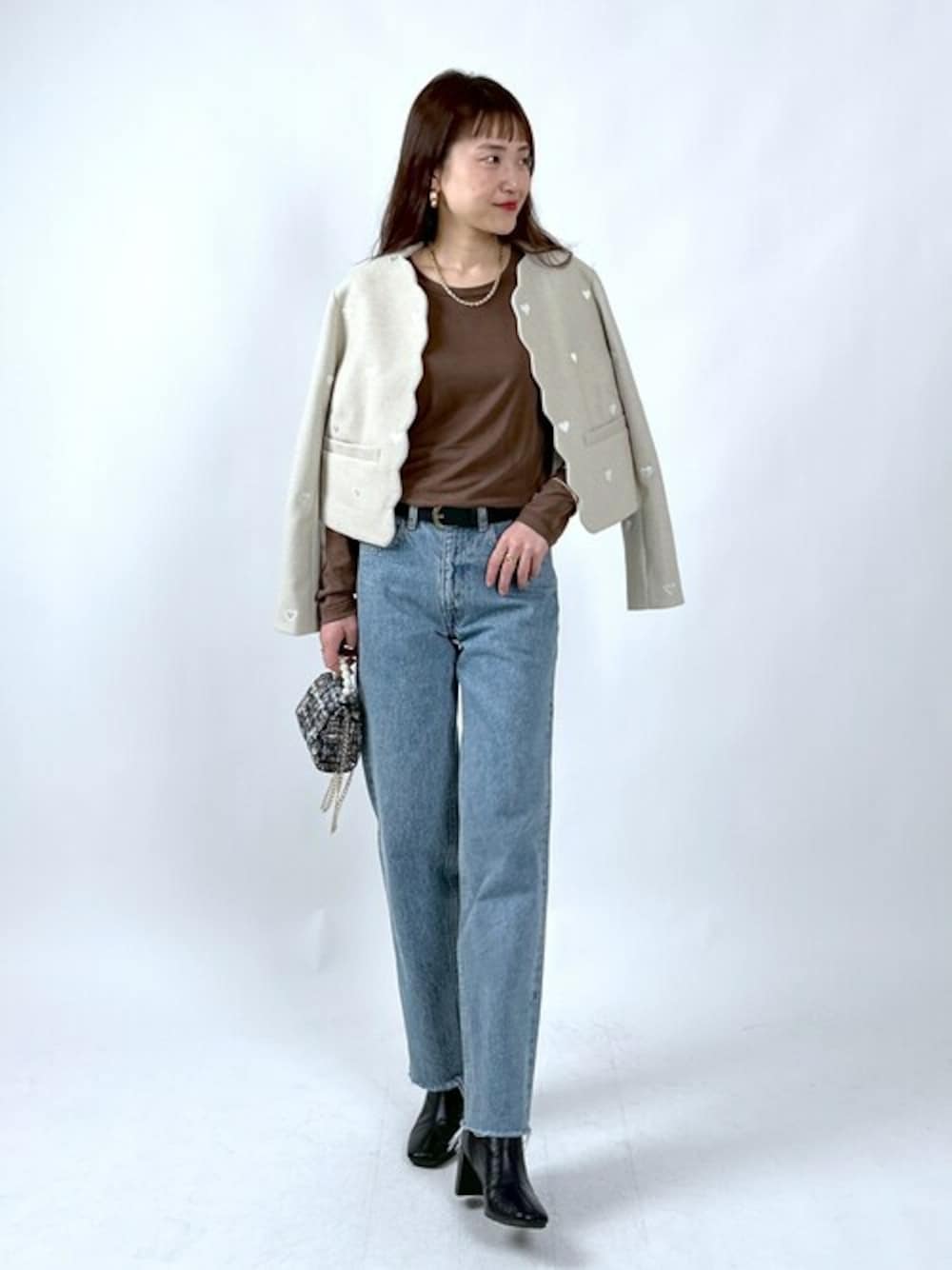 ベージュ系のノーカラージャケット、ブラウン系のTシャツ/カットソー、ブラック系のブーツを着用したレディースの冬コーディネートの1枚目の写真