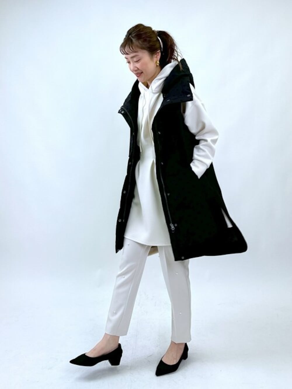 ブラック系のダウンベスト、ホワイト系のパーカー、ホワイト系のその他パンツを着用したレディースの冬コーディネートの1枚目の写真