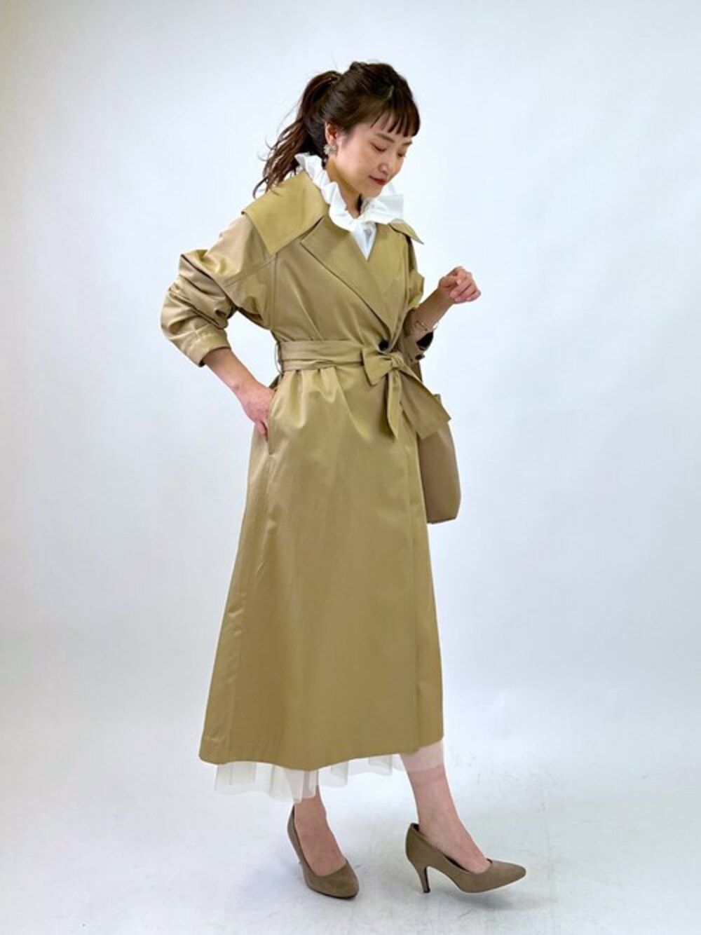 ベージュ系のトレンチコート、ホワイト系のシャツ/ブラウス、ホワイト系のスカートを着用したレディースの冬コーディネートの1枚目の写真