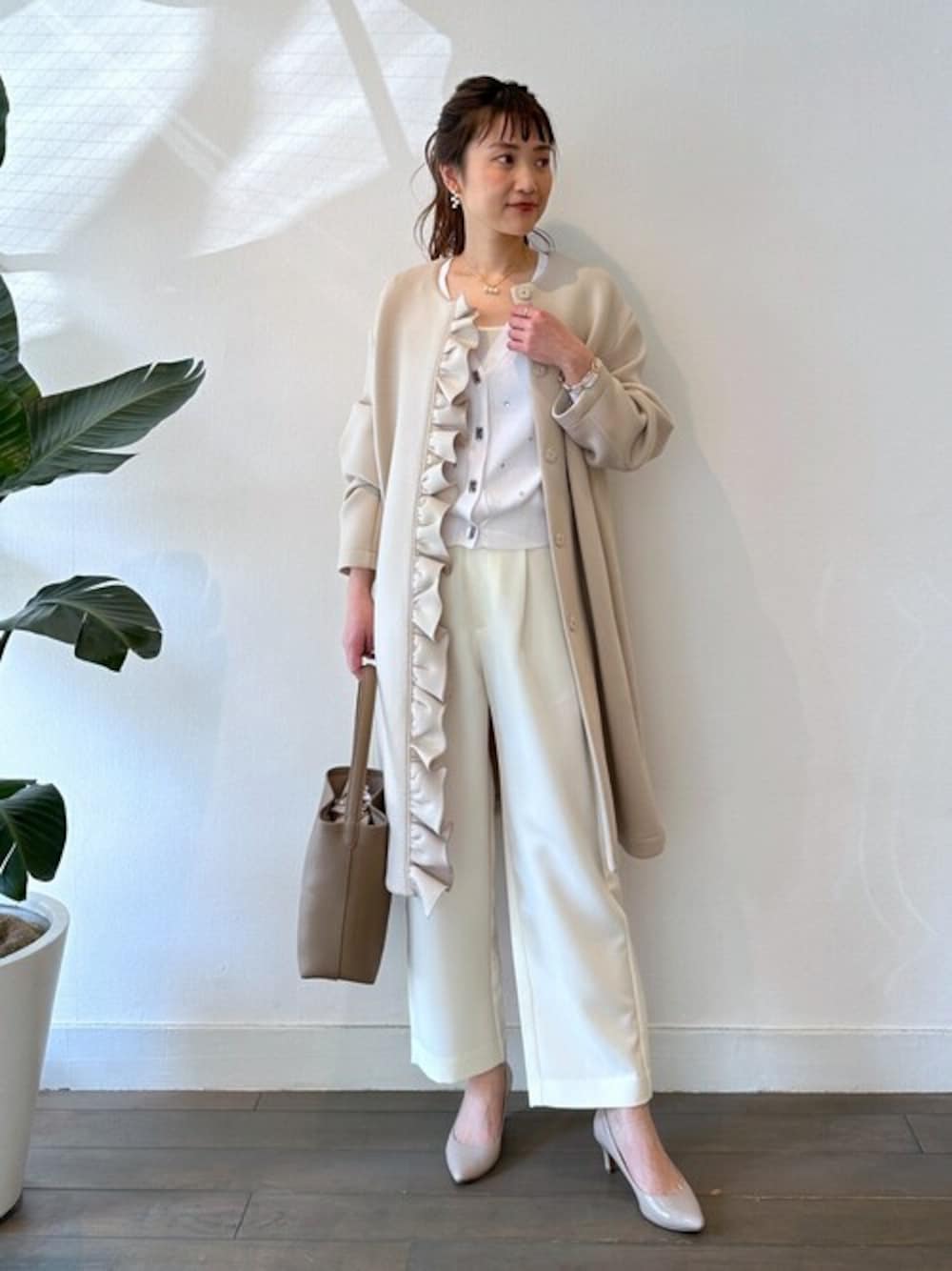 ベージュ系のノーカラーコート、ホワイト系のカーディガン/ボレロ、ホワイト系のその他パンツを着用したレディースの春コーディネートの1枚目の写真
