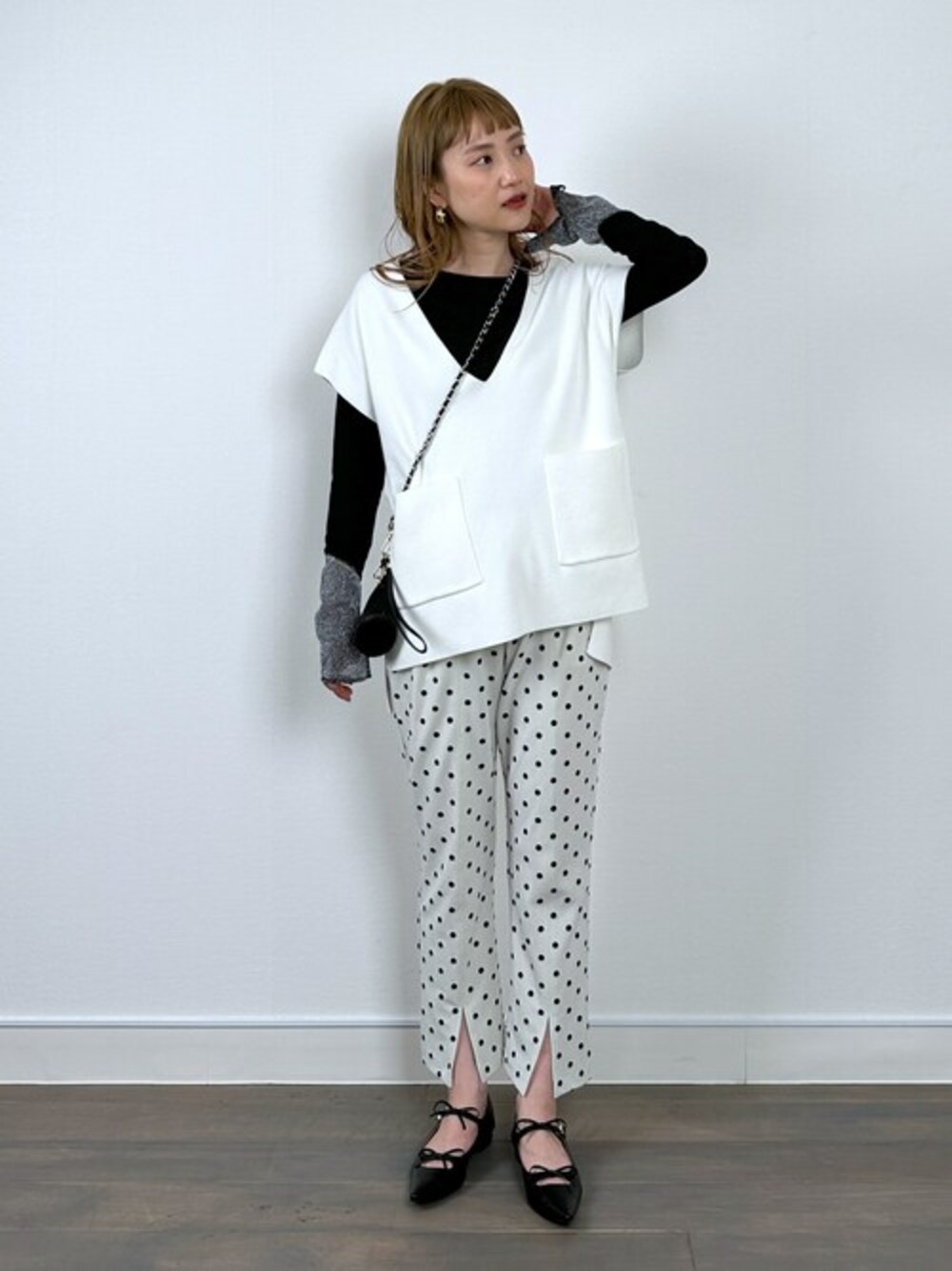 ホワイト系のニット/セーター、ブラック系のTシャツ/カットソー、ホワイト系のその他パンツを着用したレディースの春コーディネートの1枚目の写真