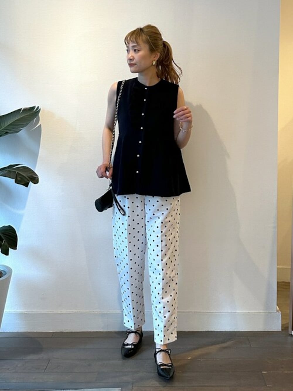 ブルー系のベスト、ホワイト系のスラックス、ブラック系のパンプスを着用したレディースの春コーディネートの1枚目の写真