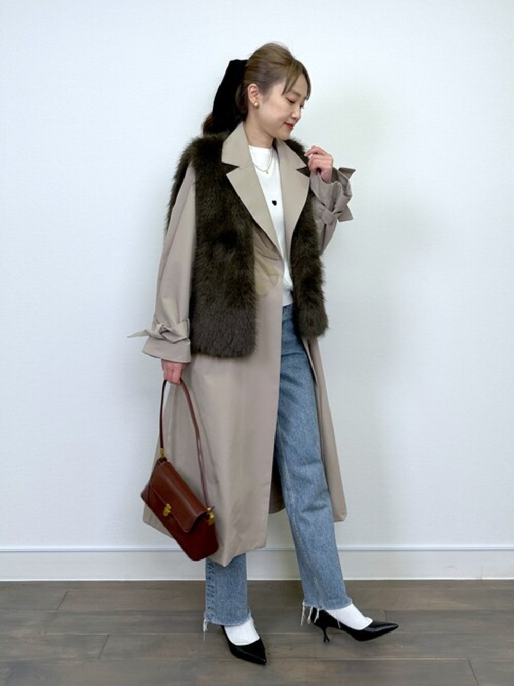 ブラウン系のベスト、ベージュ系のその他アウター、ホワイト系のニット/セーターを着用したレディースの冬コーディネートの1枚目の写真