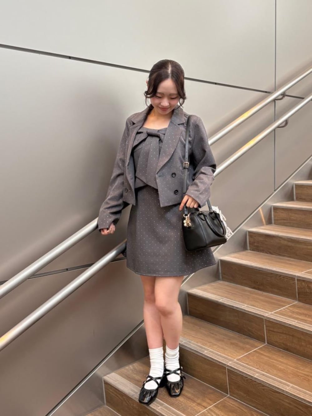 ブラック系のパンプス、ブラック系のボストンバッグ、グレー系のワンピースを着用したレディースの秋コーディネートの1枚目の写真