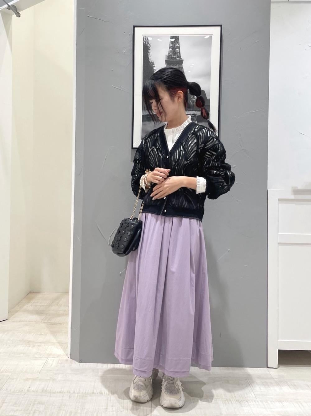 ブラック系のショルダーバッグ、ブラック系のカーディガン/ボレロ、パープル系のスカートを着用したレディースの冬コーディネートの1枚目の写真