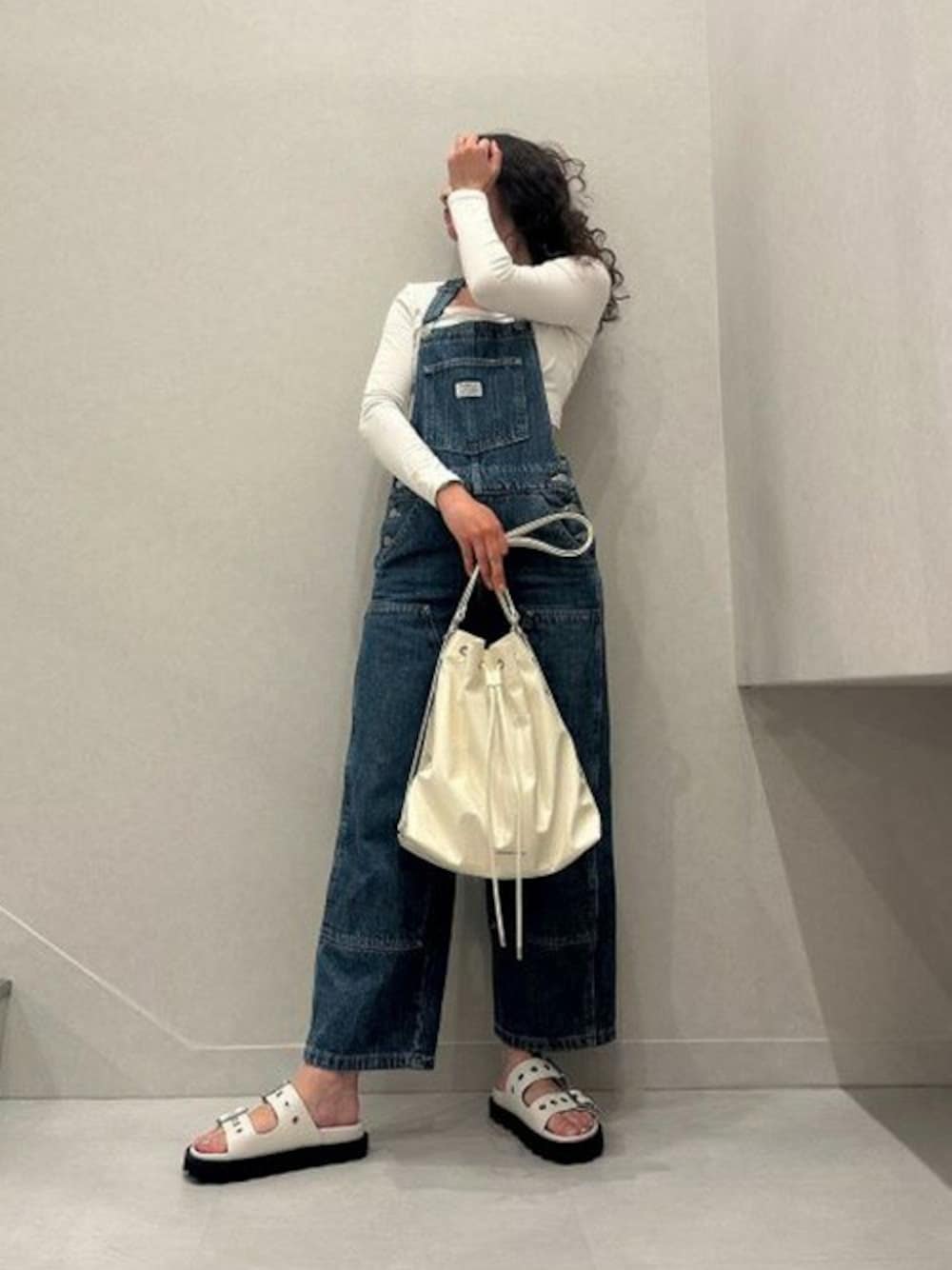 ベージュ系のショルダーバッグ、ホワイト系のサンダルを着用したレディースの夏コーディネートの1枚目の写真