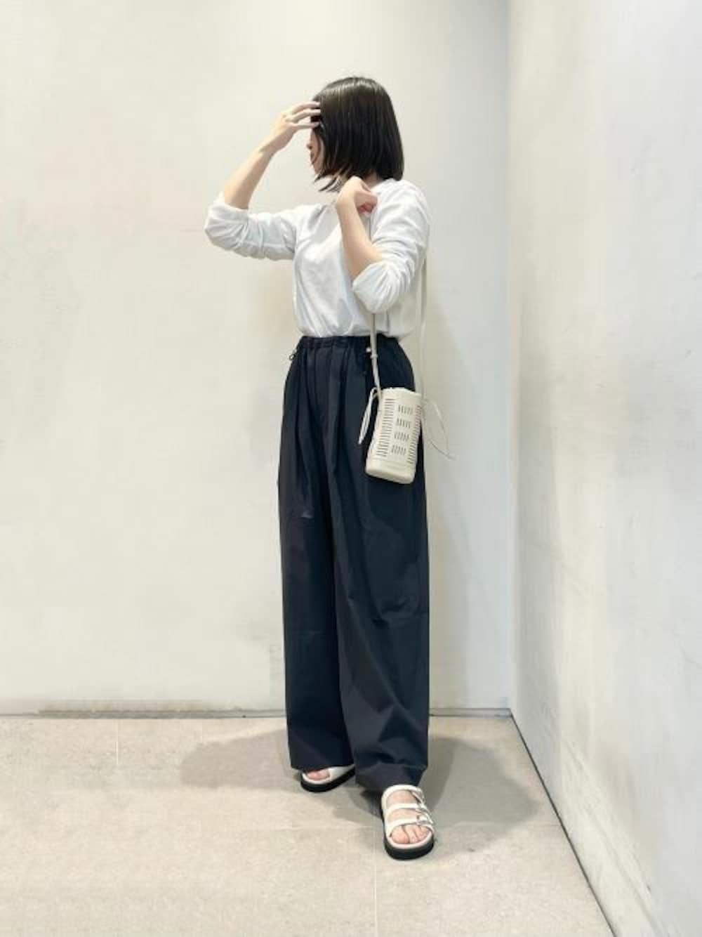 ベージュ系のショルダーバッグ、ホワイト系のサンダルを着用したレディースの夏コーディネートの1枚目の写真