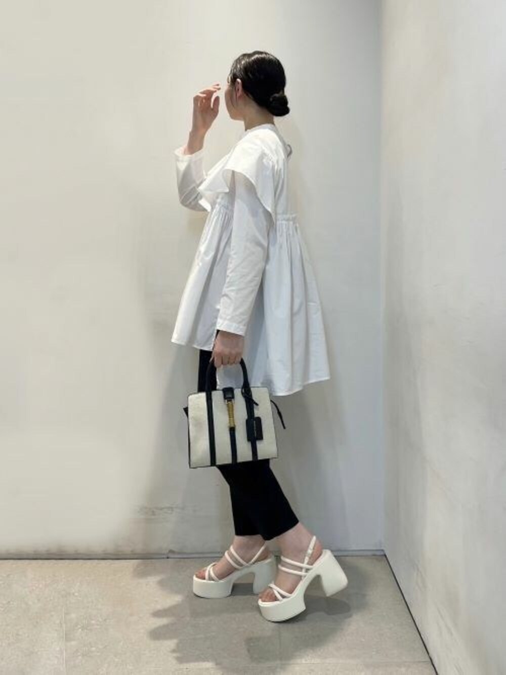 ブラック系のトートバッグ、ホワイト系のサンダルを着用したレディースの夏コーディネートの1枚目の写真