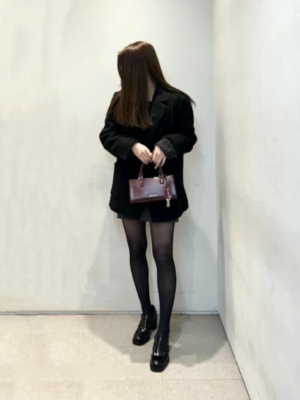 パープル系のトートバッグ、ブラック系のローファーを着用したレディースの冬コーディネートの1枚目の写真
