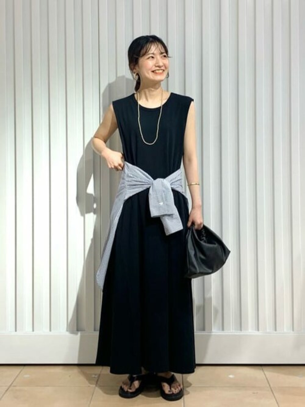 ブラック系のワンピース、ブラック系のハンドバッグを着用したレディースの夏コーディネートの1枚目の写真