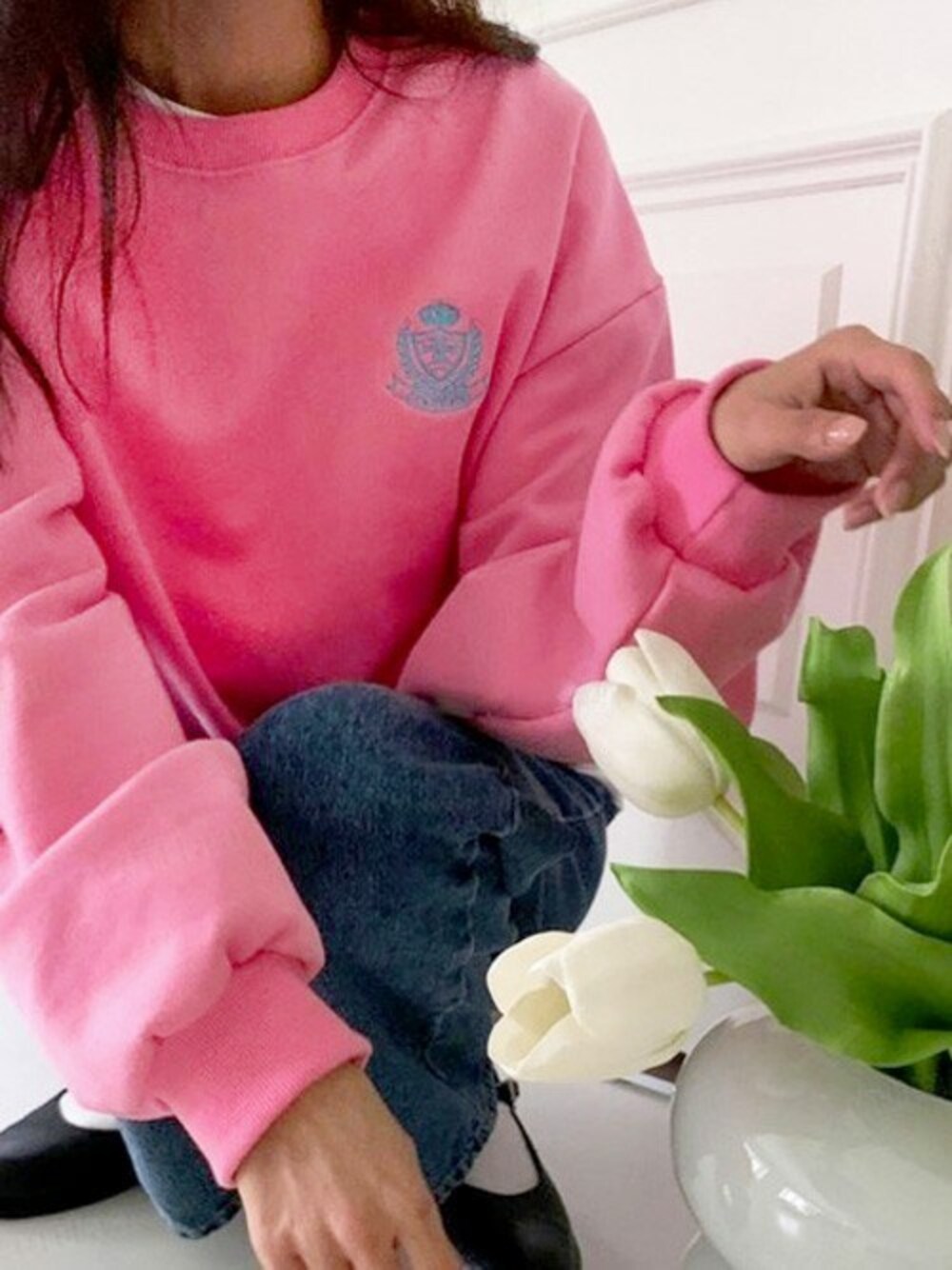 ピンク系のスウェット、ブルー系のデニムパンツを着用したレディースの冬コーディネートの1枚目の写真