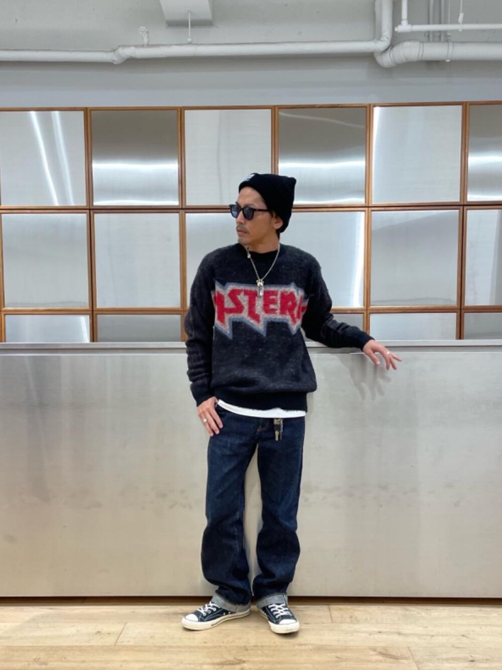 ブルー系のデニムパンツ、ホワイト系のTシャツ/カットソー、ブラック系のニット/セーターを着用したメンズの秋コーディネートの1枚目の写真