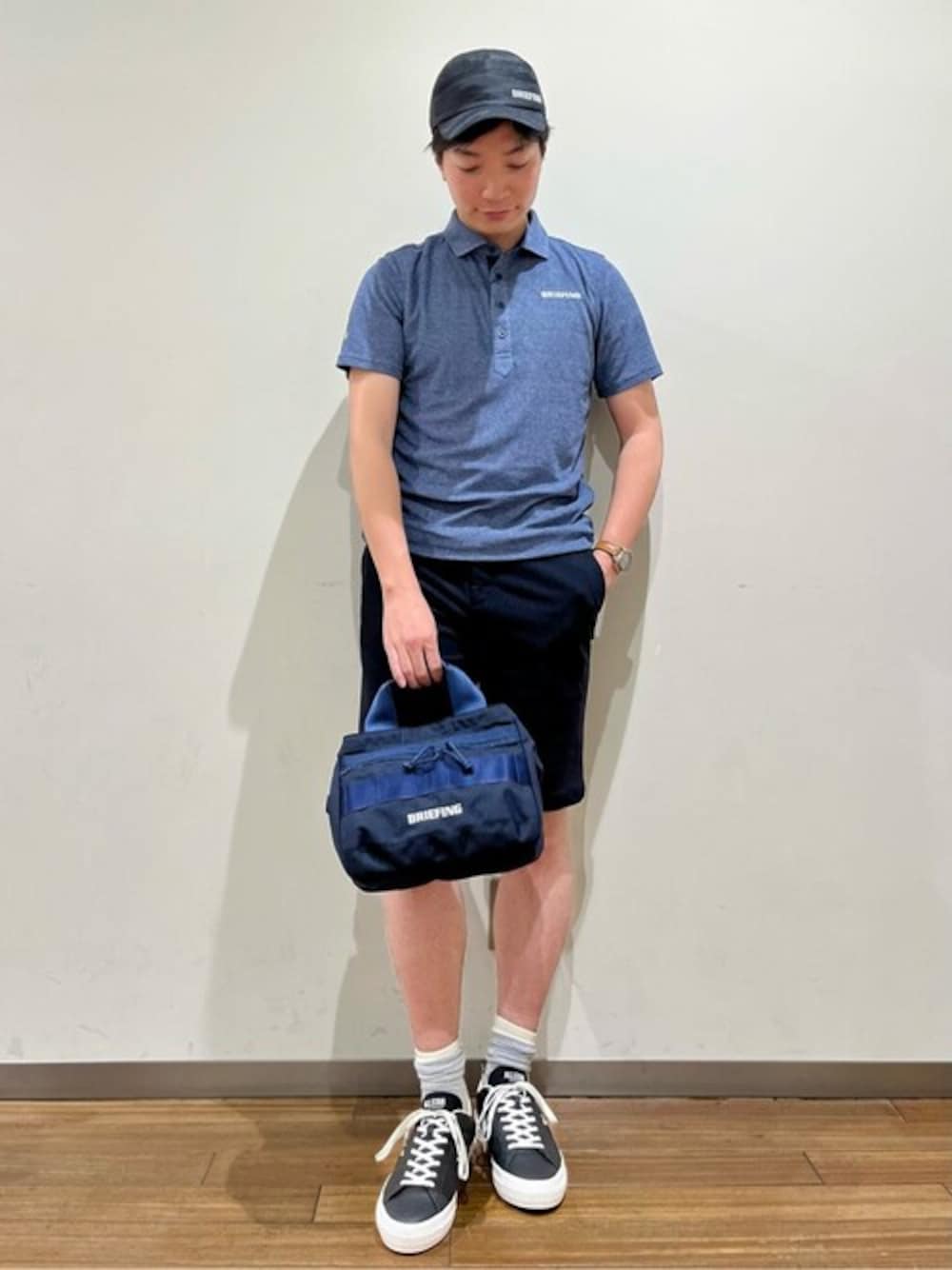 ブルー系のポロシャツ、ブラック系のその他パンツ、ブルー系のトートバッグを着用したメンズの春コーディネートの1枚目の写真