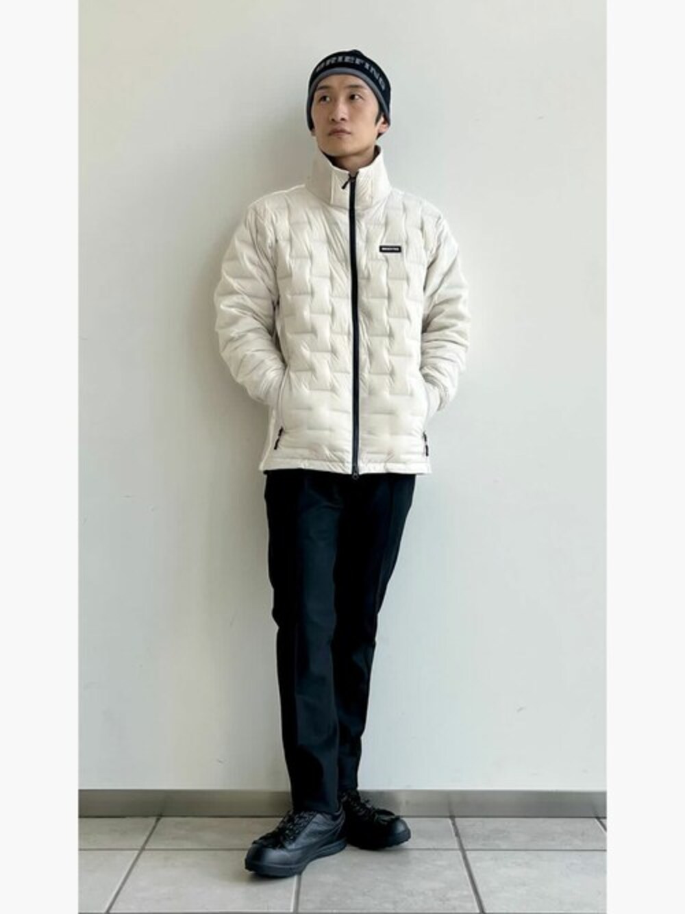 ブラック系のその他パンツ、ベージュ系のダウンジャケット/コート、ブラック系のキャップを着用したメンズの冬コーディネートの1枚目の写真