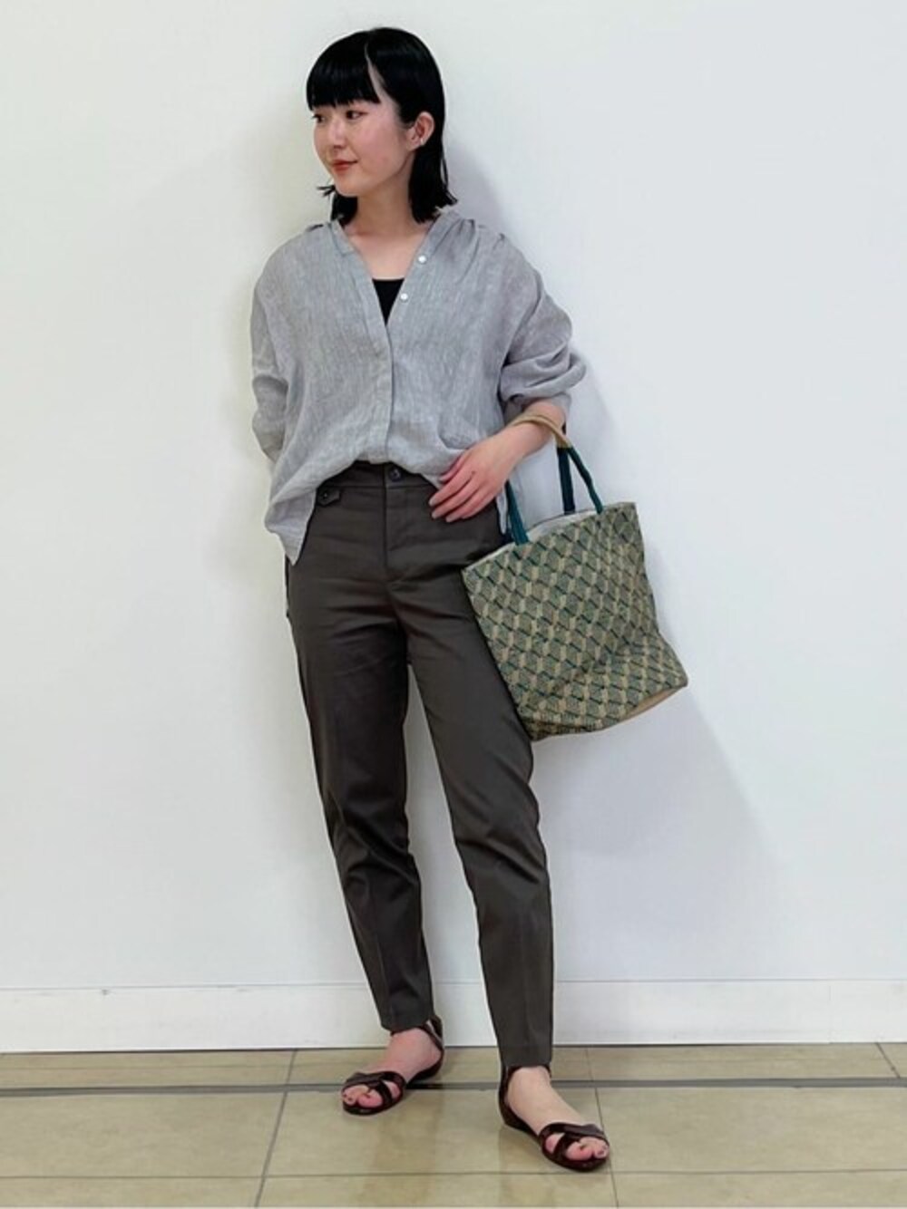 グレー系のシャツ/ブラウス、グレー系のタンクトップ、グリーン系のトートバッグを着用したレディースの春コーディネートの1枚目の写真