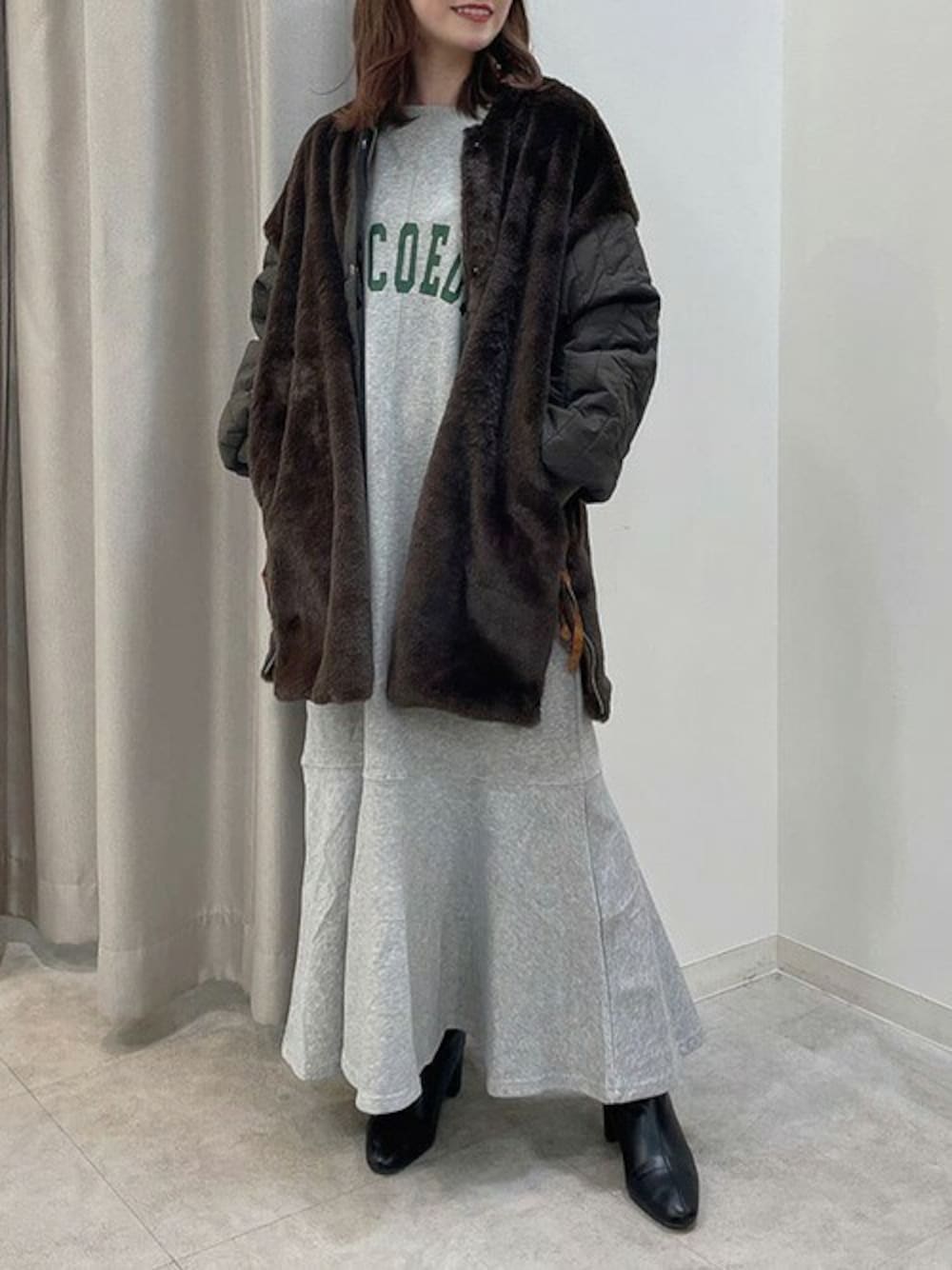 グレー系のワンピース、グリーン系のブルゾン、ブラック系のブーツを着用したレディースの冬コーディネートの1枚目の写真