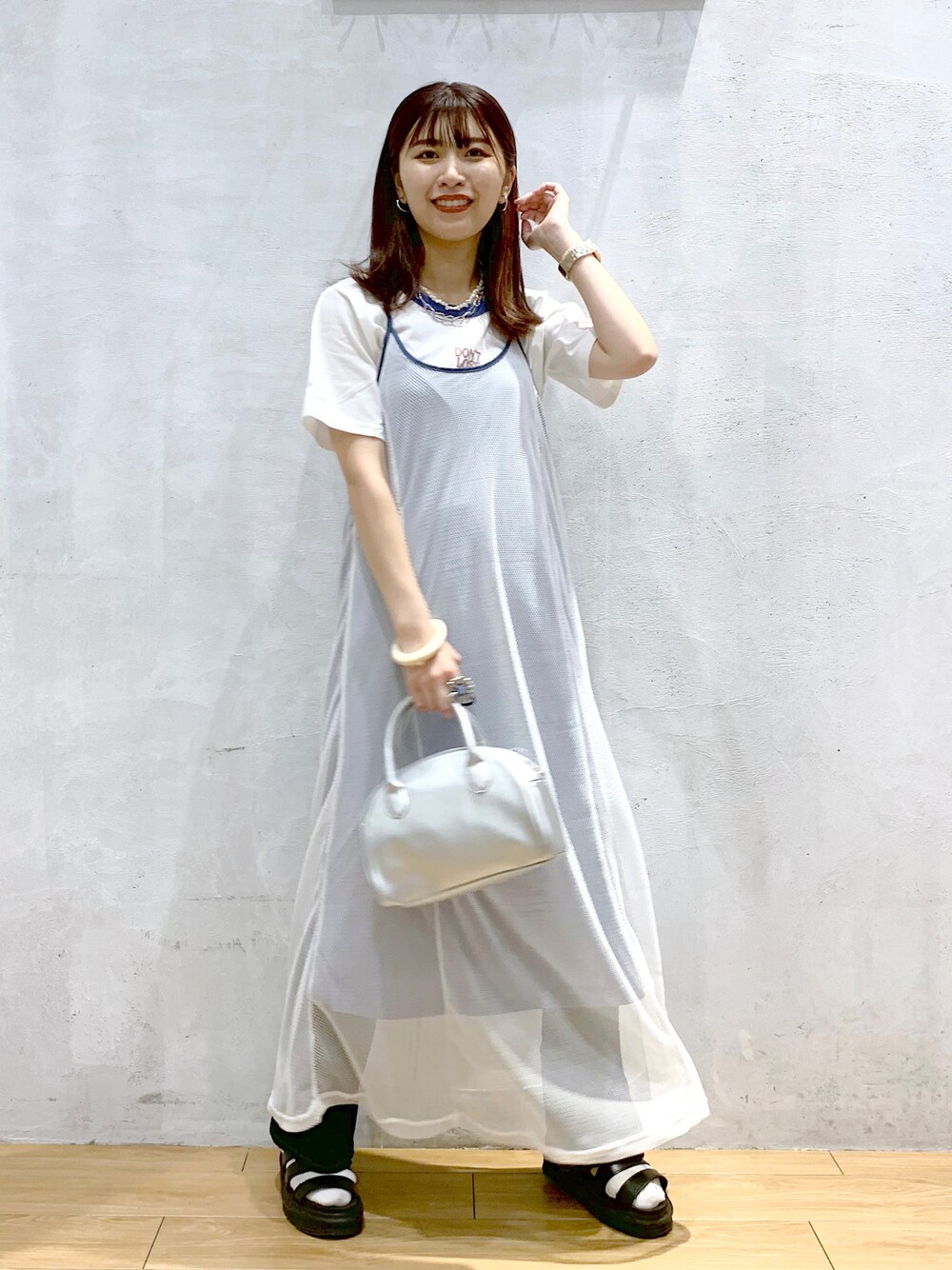 シルバー系のショルダーバッグ、ホワイト系のワンピース、ホワイト系のTシャツ/カットソーを着用したレディースの夏コーディネートの1枚目の写真