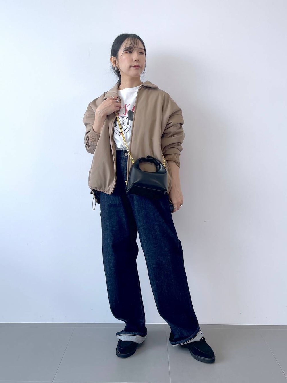 ブルー系のデニムパンツ、ブラック系のショルダーバッグ、ホワイト系のTシャツ/カットソーを着用したレディースの秋コーディネートの1枚目の写真