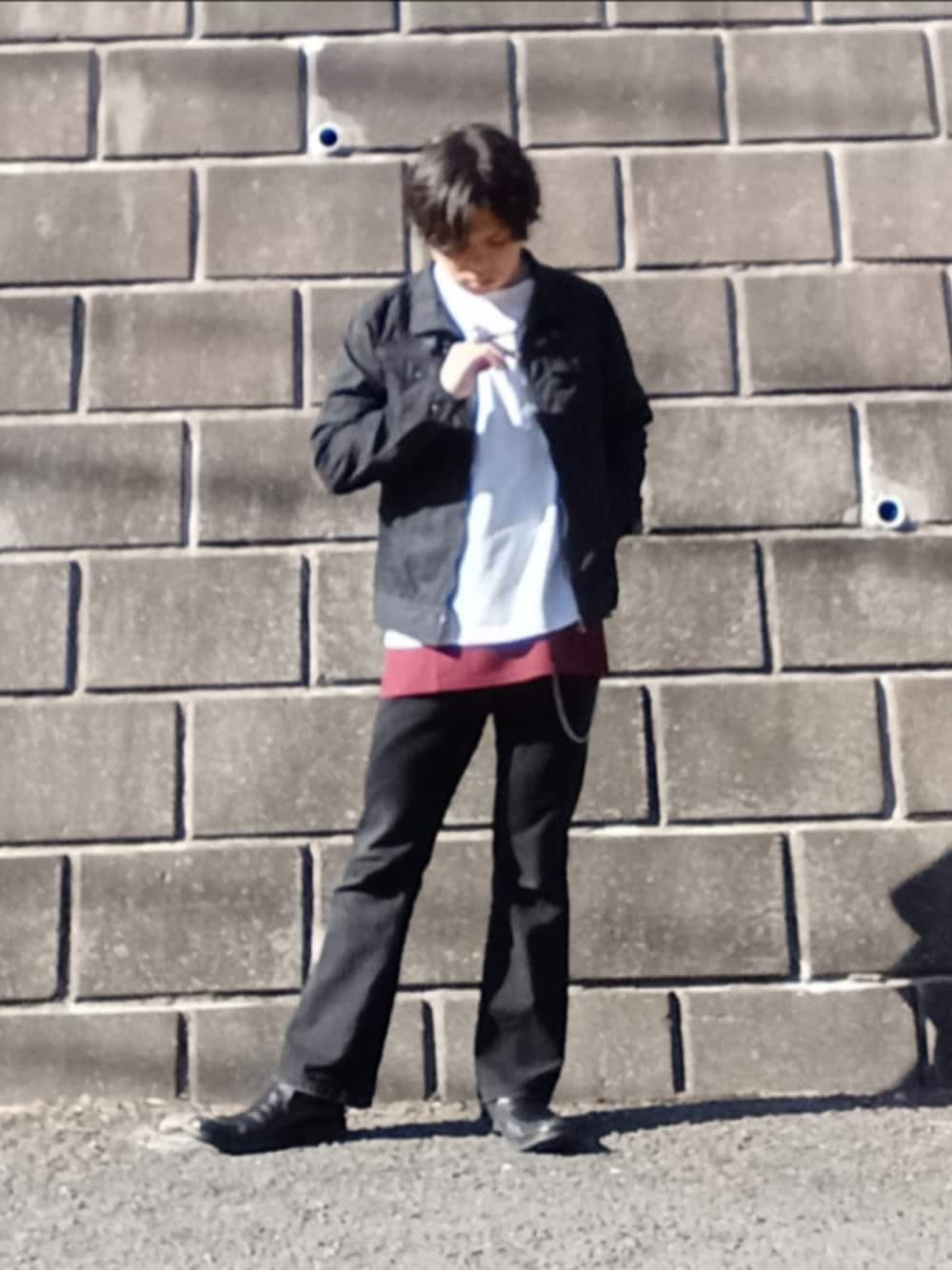 ブラック系のデニムパンツ、ブラック系のスリッポン、レッド系のタンクトップを着用したメンズの冬コーディネートの1枚目の写真