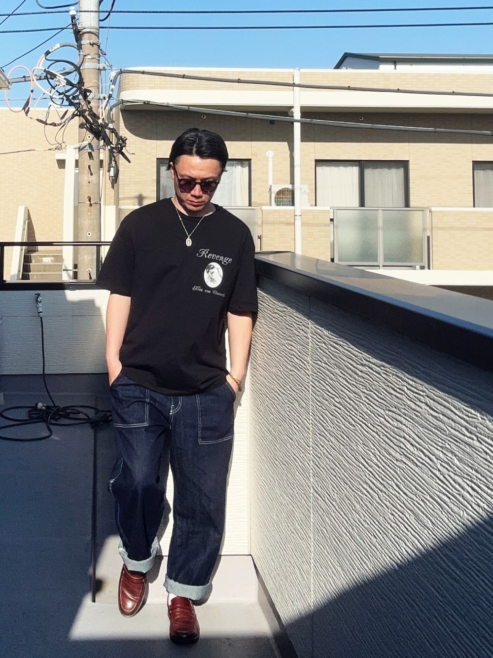 ブルー系のデニムパンツ、ブラック系のTシャツ/カットソー、ブラウン系のローファーを着用したメンズの春コーディネートの1枚目の写真