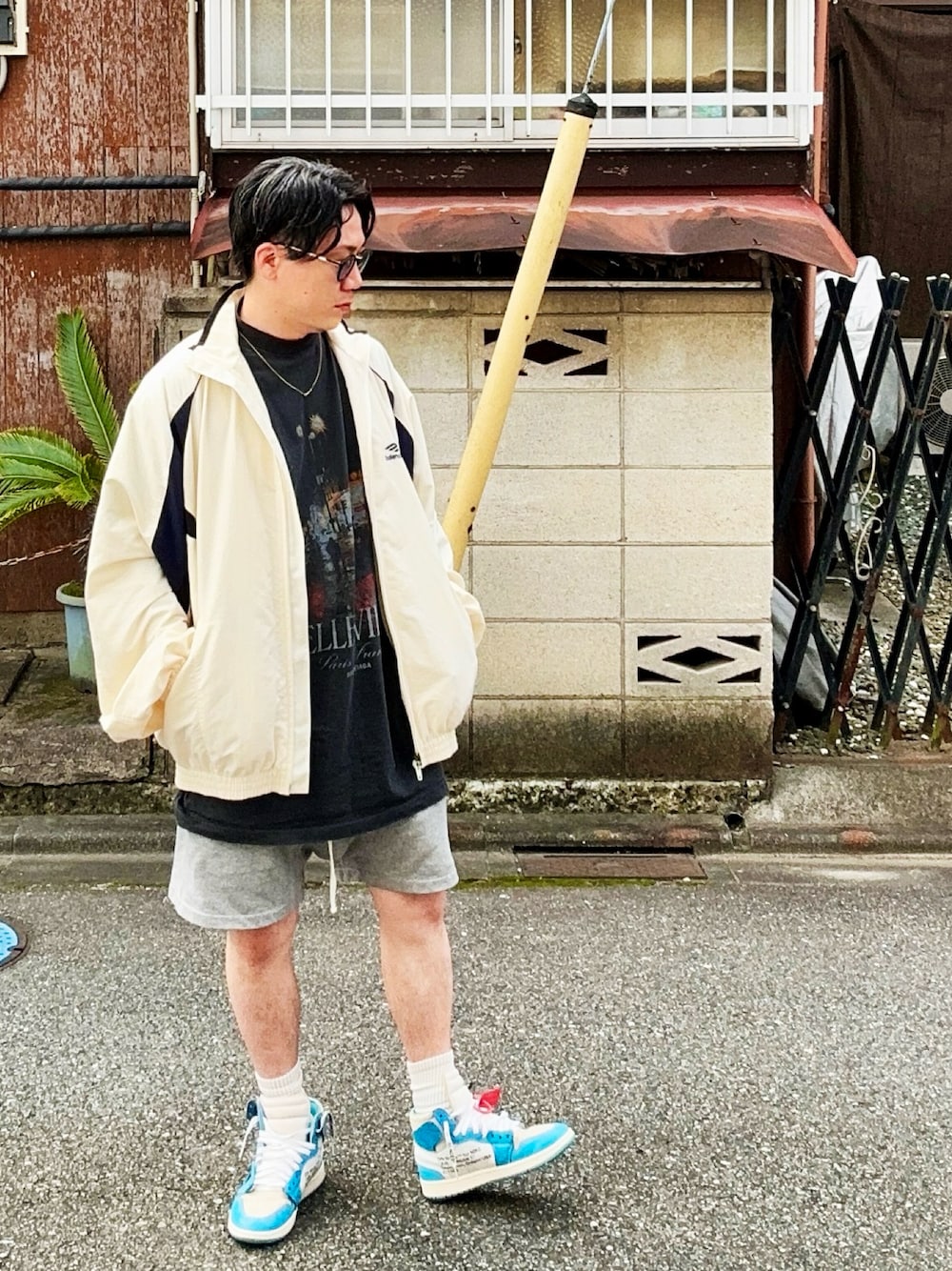ブラック系のTシャツ/カットソー、ホワイト系のナイロンジャケット、グレー系のパンツを着用したメンズの秋コーディネートの1枚目の写真