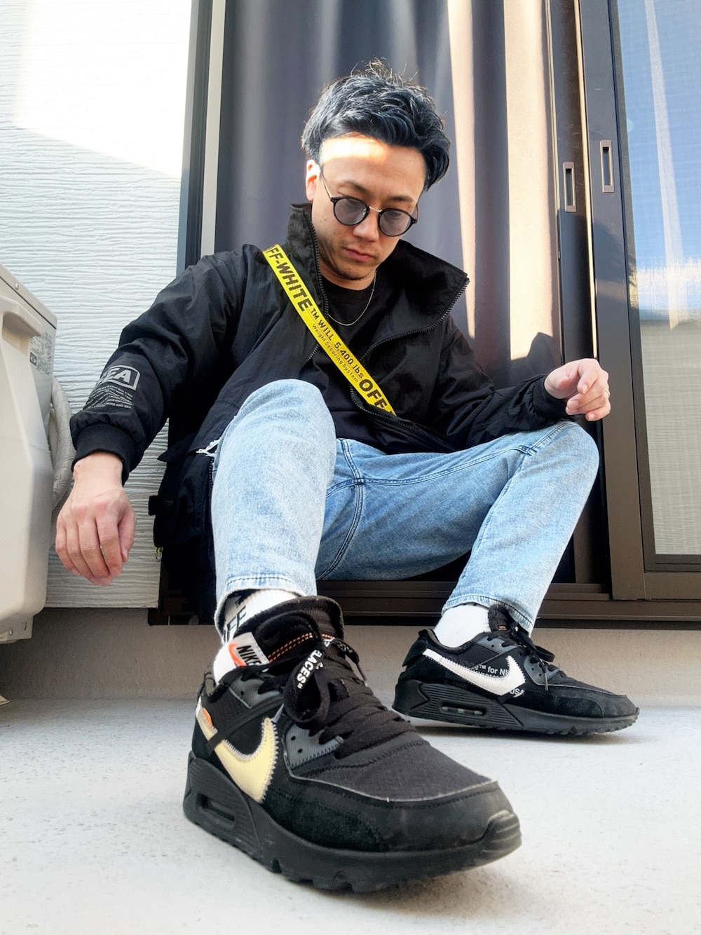 ブルー系のデニムパンツ、ブラック系のショルダーバッグ、ブラック系のTシャツ/カットソーを着用したメンズの冬コーディネートの1枚目の写真