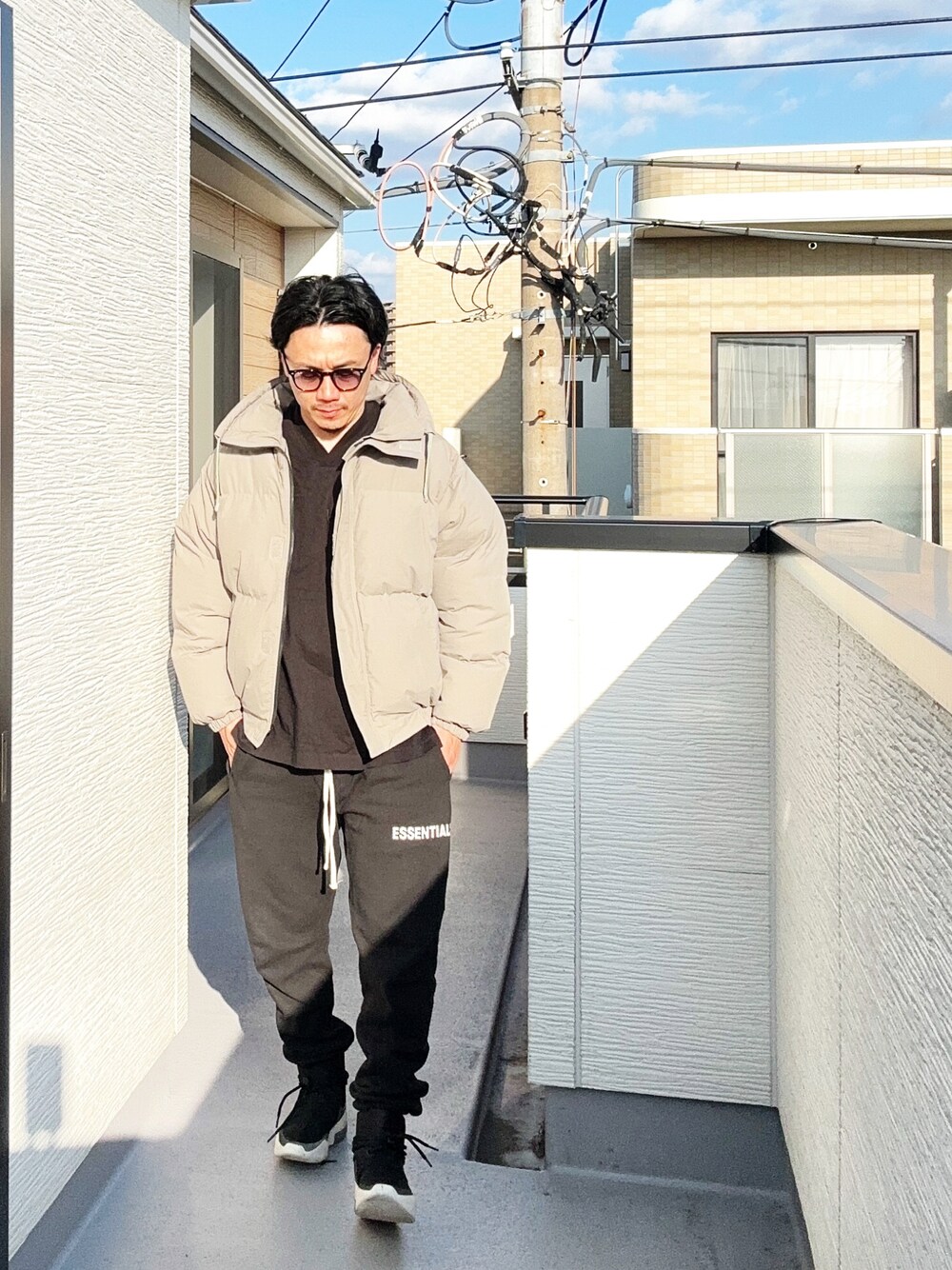 ブラック系のTシャツ/カットソー、グレー系のダウンジャケット/コート、ブラック系のスウェットパンツを着用したメンズの秋コーディネートの1枚目の写真