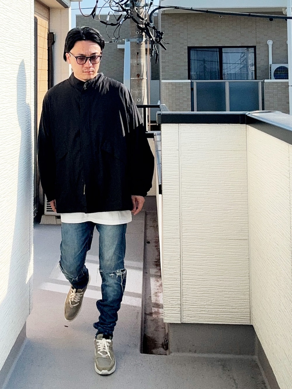 ブラック系のブルゾン、ホワイト系のTシャツ/カットソー、ブルー系のデニムパンツを着用したメンズの秋コーディネートの1枚目の写真