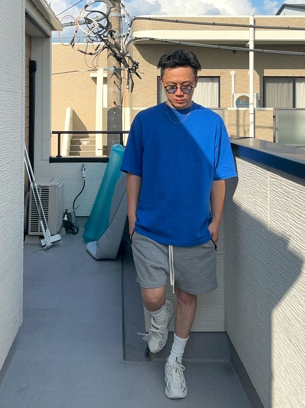 ブルー系のTシャツ/カットソー、グレー系のパンツ、ホワイト系のスニーカーを着用したメンズの夏コーディネートの1枚目の写真