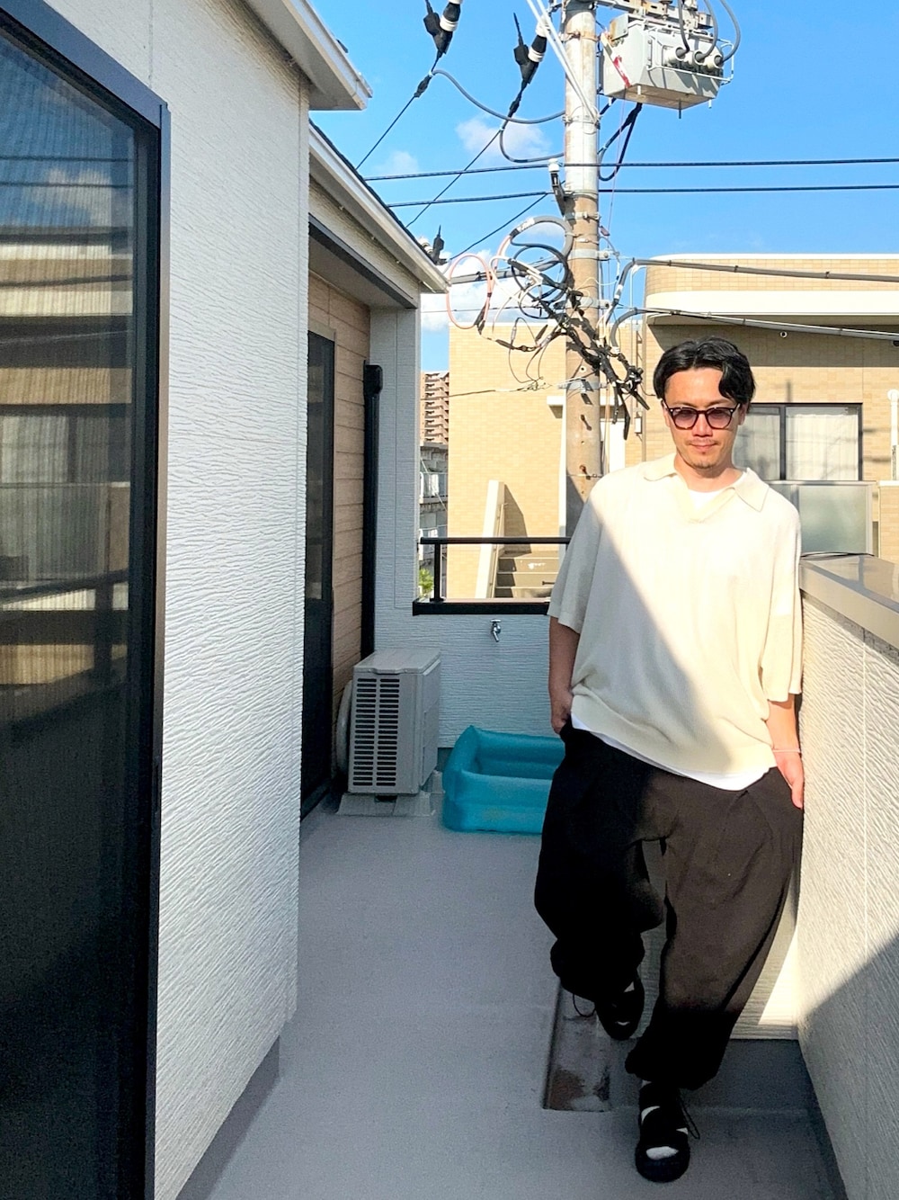 ホワイト系のトップス、ブラック系のスウェットパンツ、ブラック系のサンダルを着用したメンズの秋コーディネートの1枚目の写真