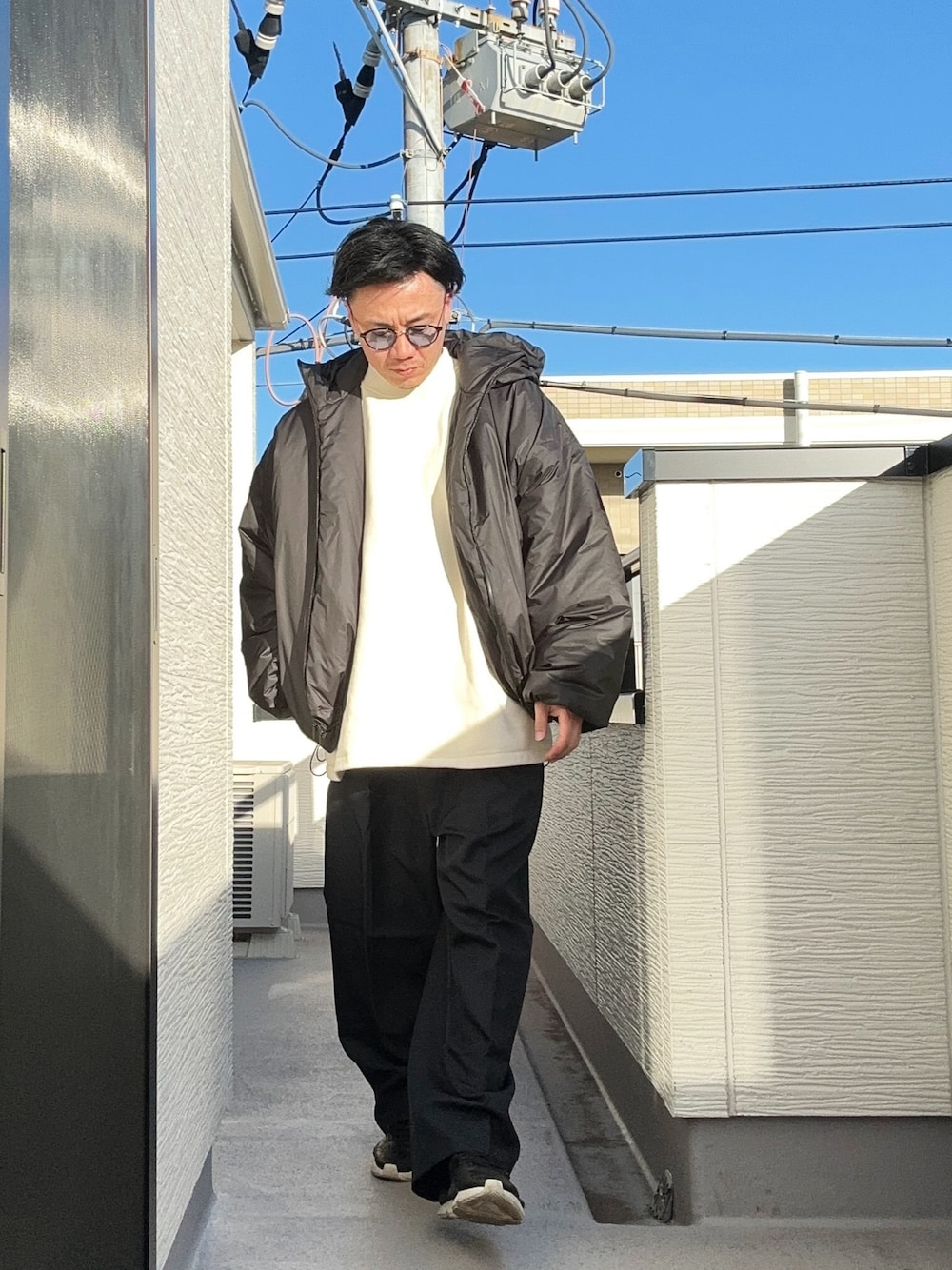 ベージュ系のTシャツ/カットソー、ブラック系のジャケット/アウター、ブルー系のスラックスを着用したメンズの冬コーディネートの1枚目の写真