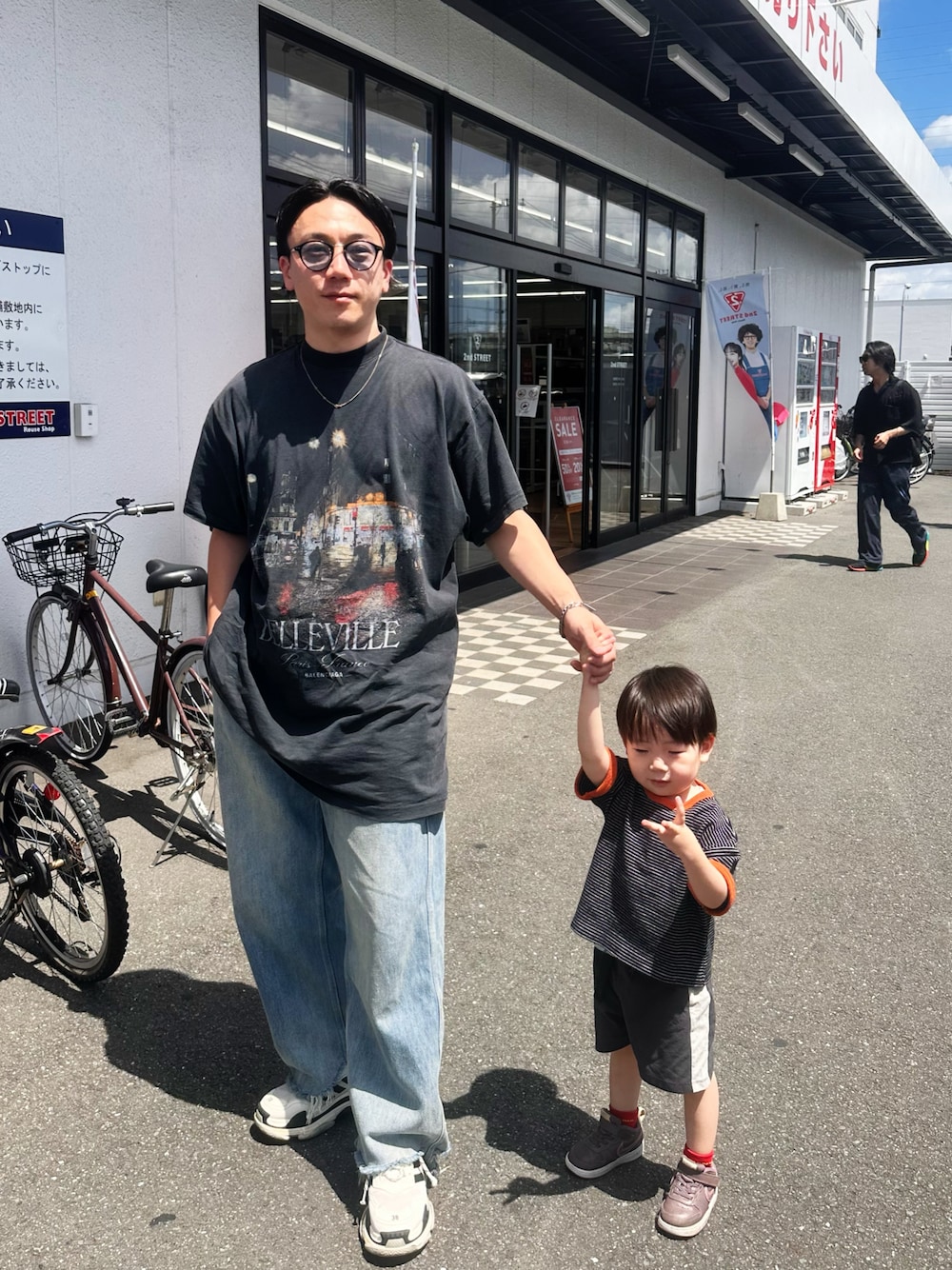 ブルー系のデニムパンツ、ブラック系のTシャツ/カットソー、ホワイト系のシューズを着用したメンズの夏コーディネートの1枚目の写真